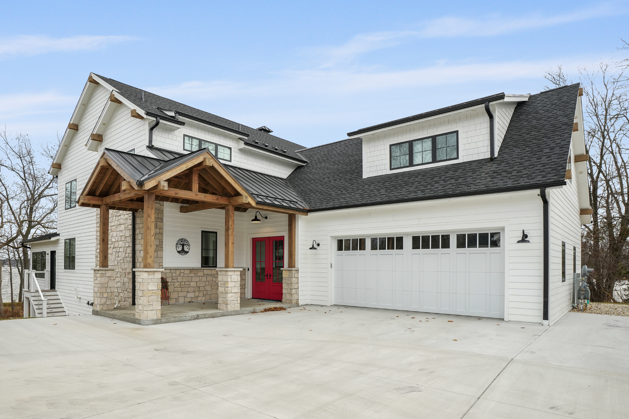 Exterior of a Luxury Custom Home Builder's project with white siding, stone accents, and red front doors.