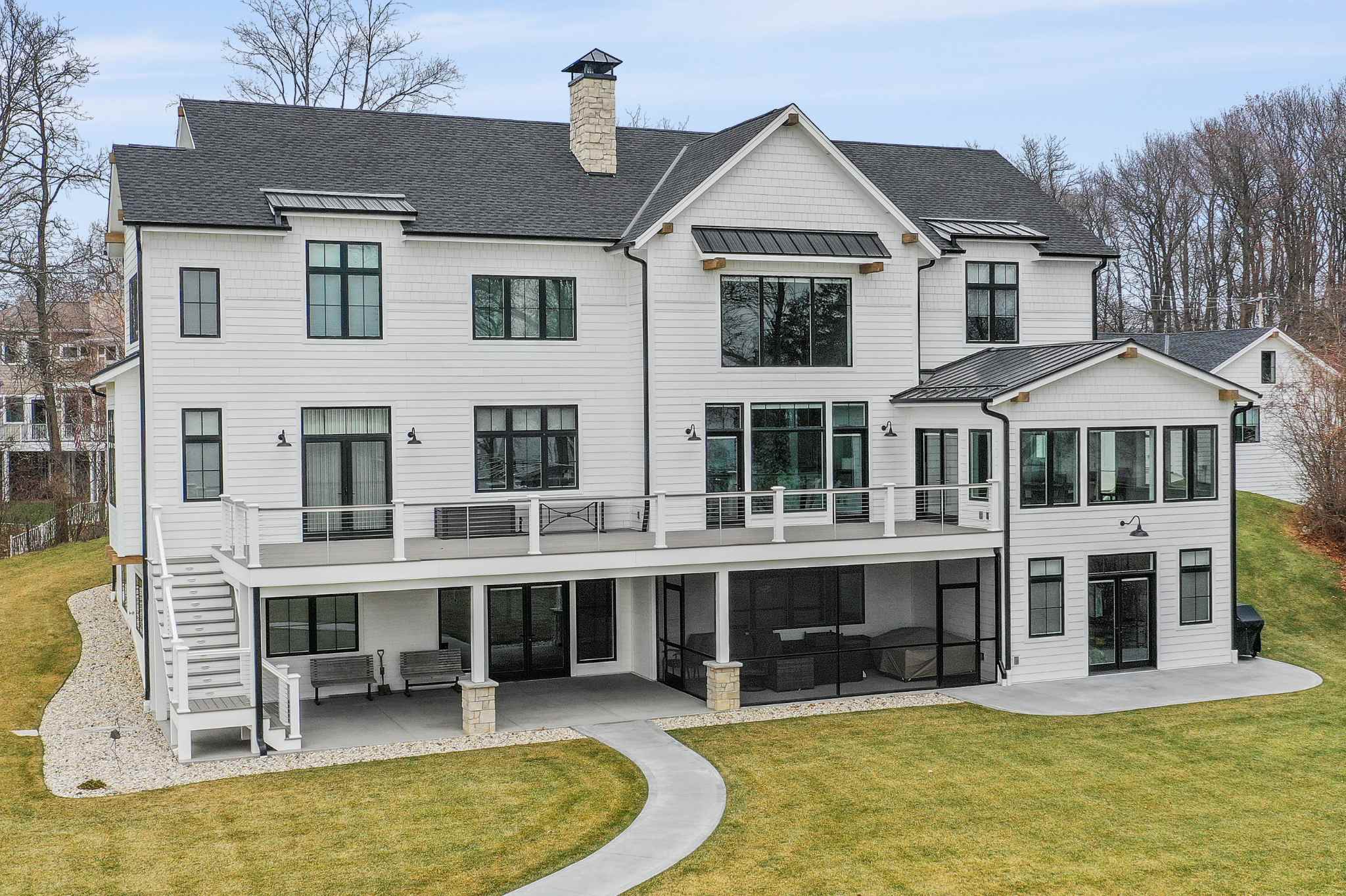 Luxury homes builder's spacious backyard view of a white house with a large deck.