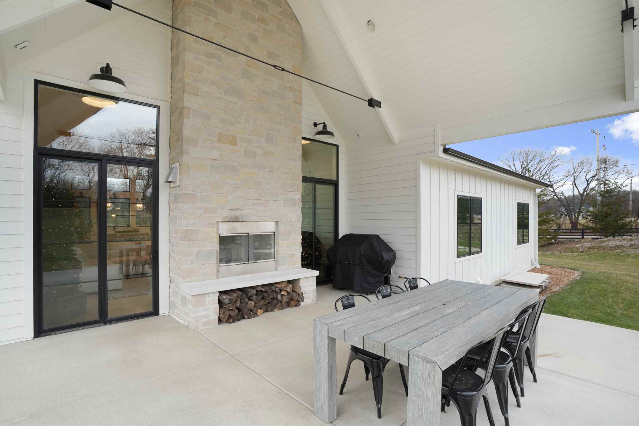 Luxury homes builder's cozy outdoor dining area featuring a stone fireplace.