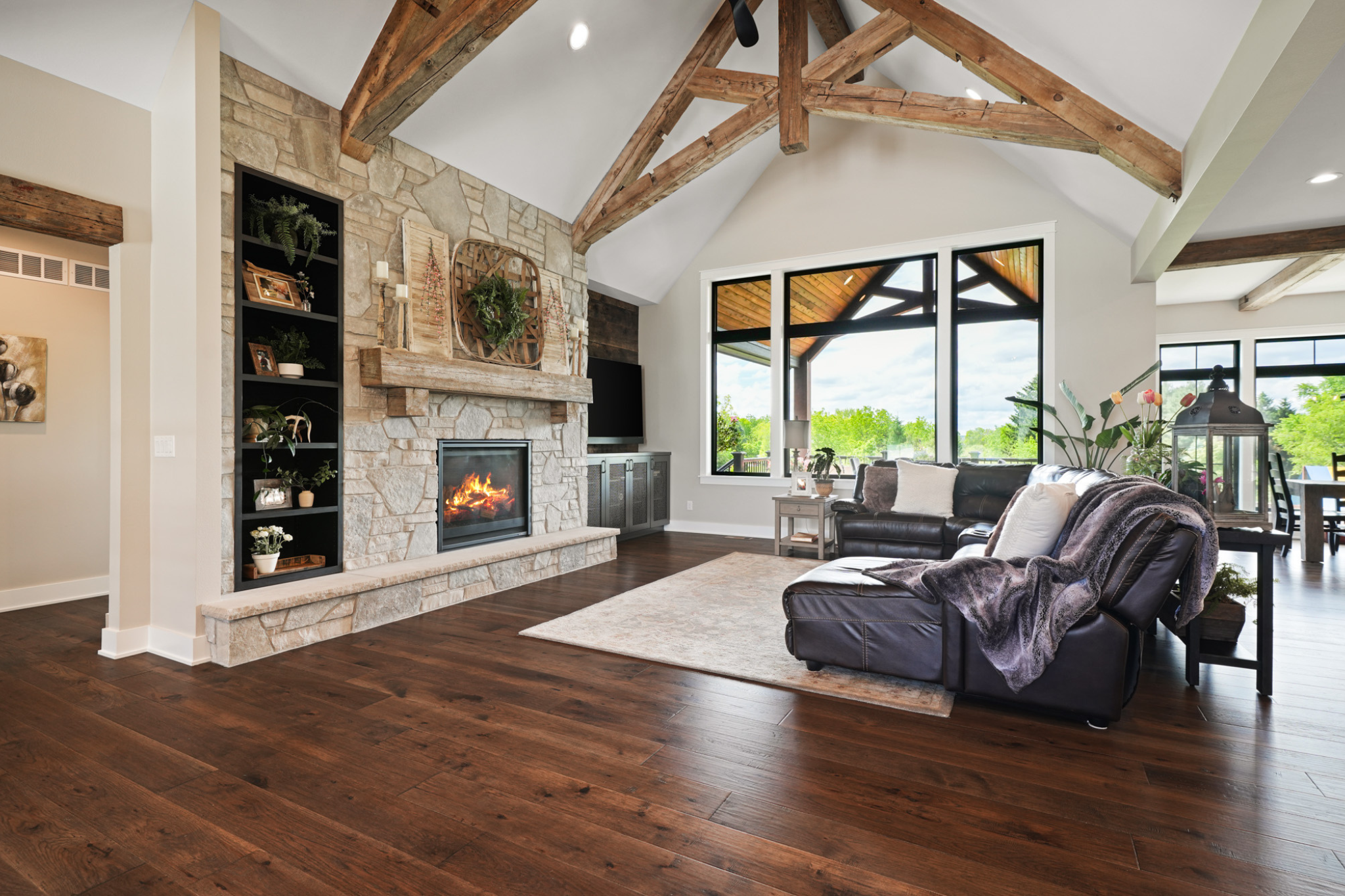 One story vs two story house: Spacious living room with rustic wooden beams and a stone fireplace.