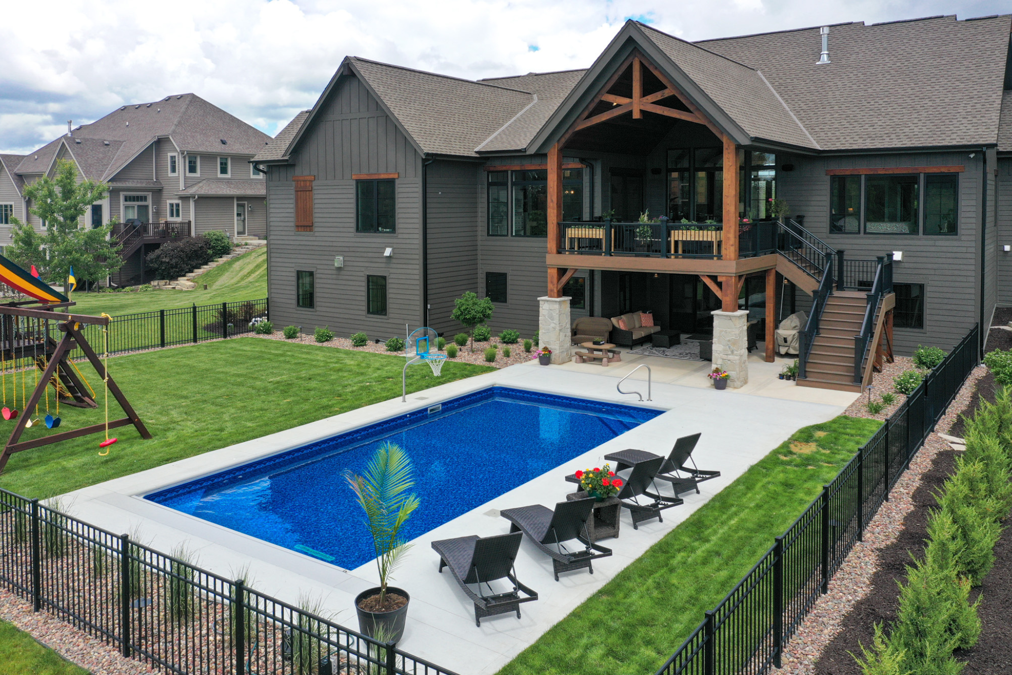 One story vs two story house: Backyard view of a two-story house with a pool and outdoor seating area.