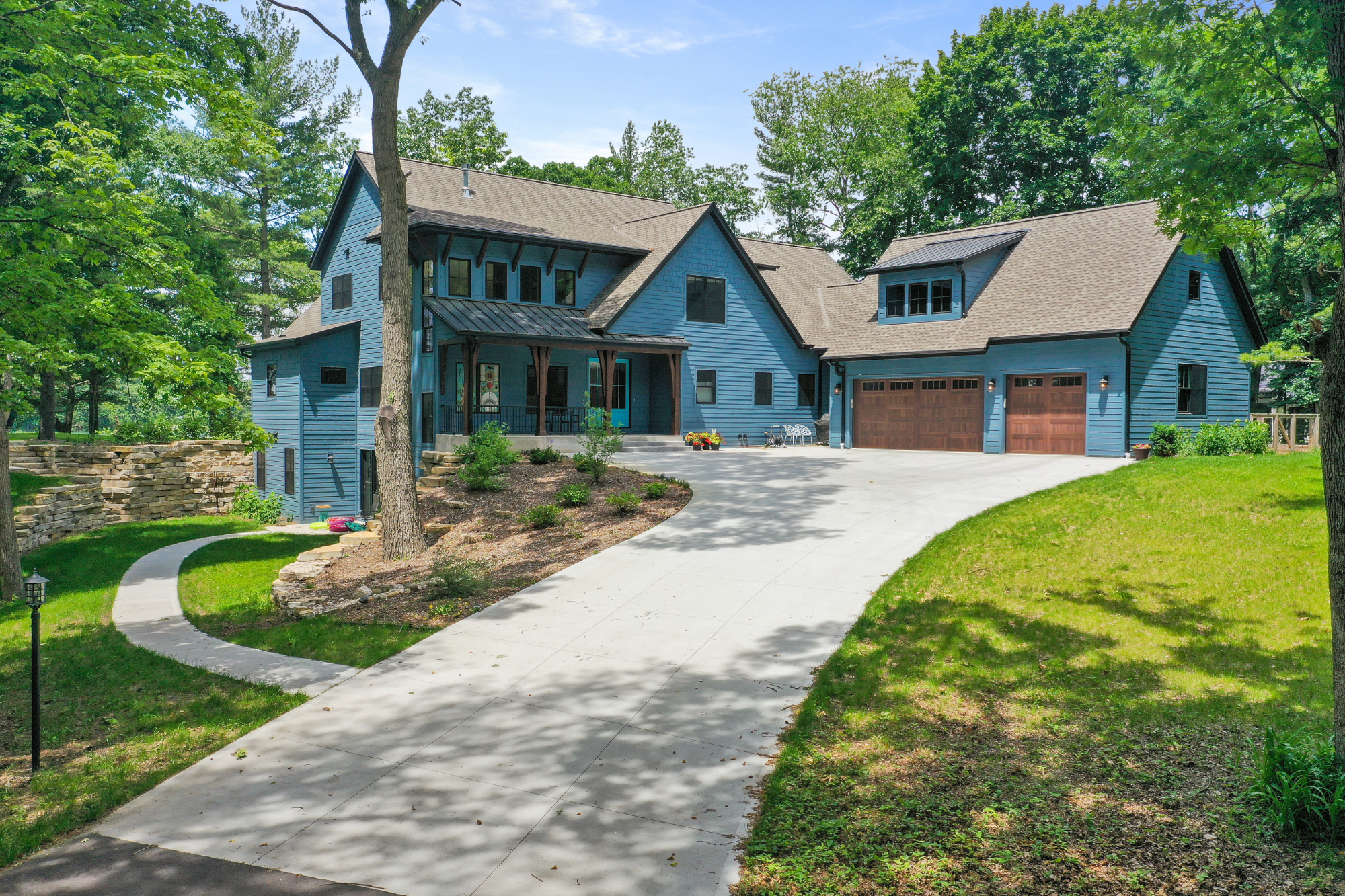 A spacious custom home in Brookfield featuring a large driveway and elevated design elements for flood resistance.