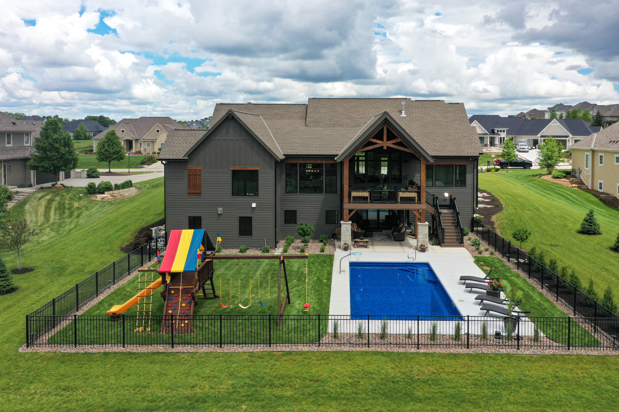 A custom home in Waukesha featuring a backyard with a pool and children's play area, designed by top home builders in Waukesha WI.