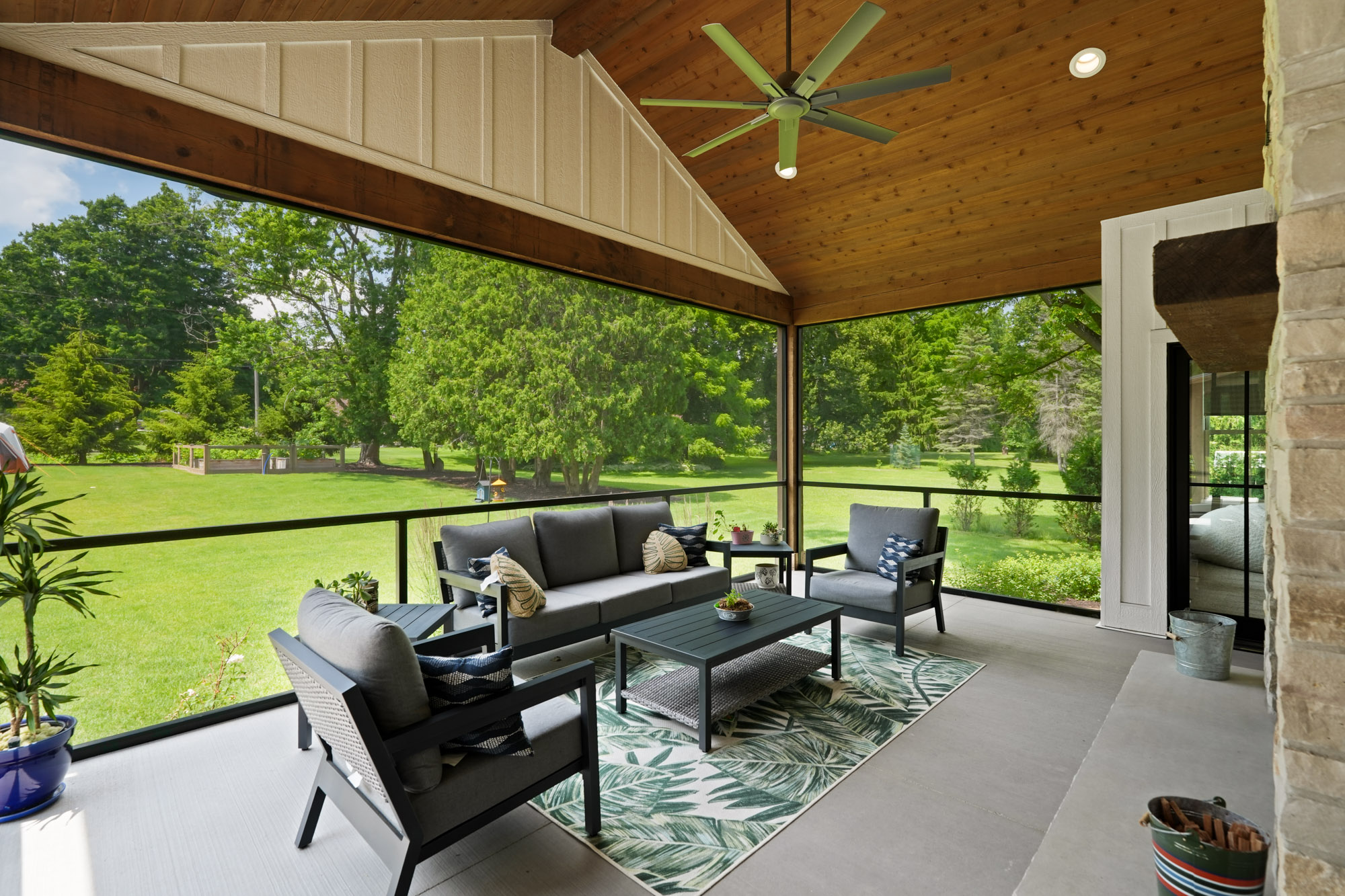 Camera1_115 Spacious screened-in porch with modern outdoor furniture and vaulted wood ceiling, built by luxury home builders in Brookfield, Wisconsin, overlooking a lush backyard.