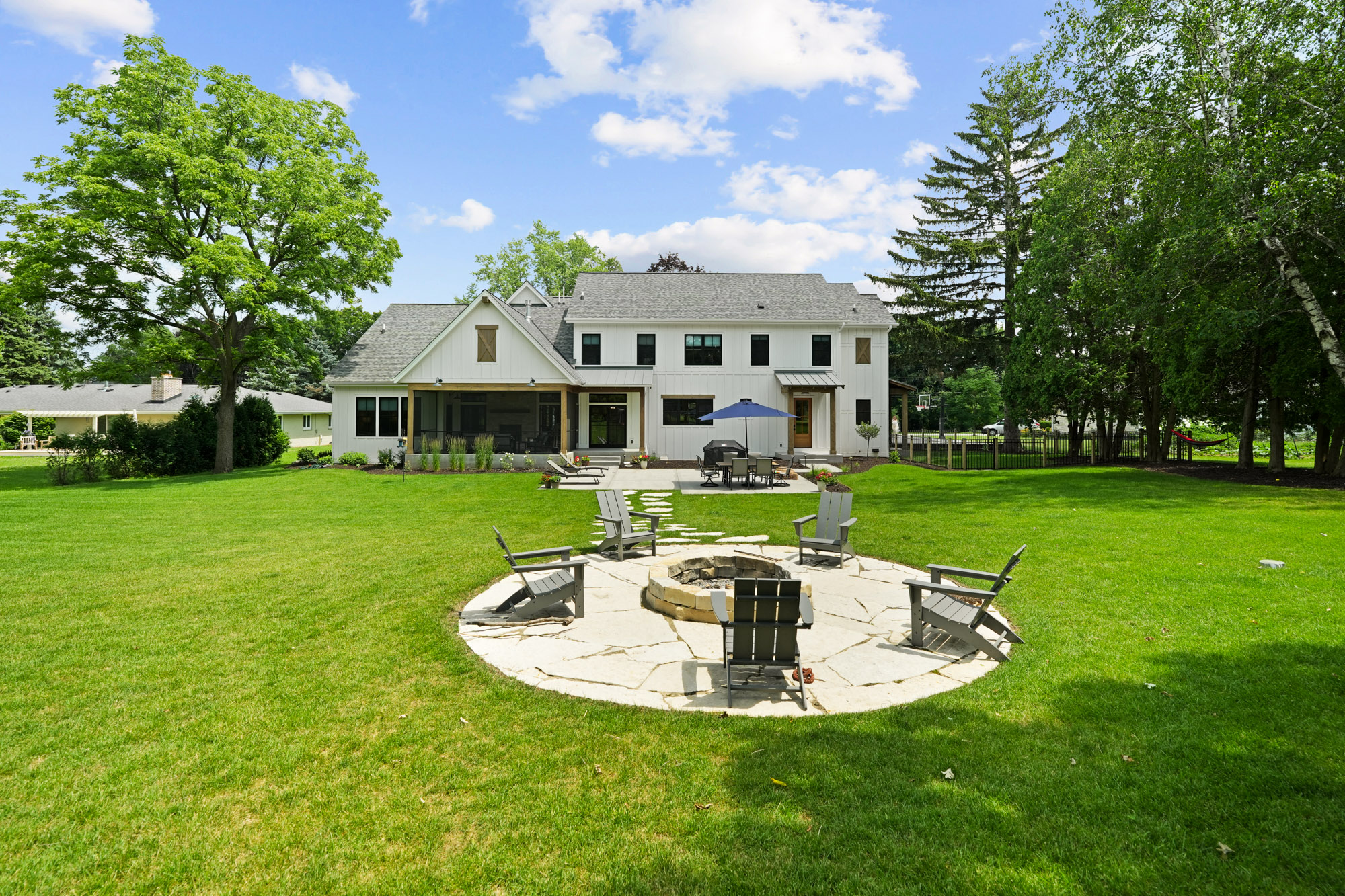 Spacious backyard featuring a stone fire pit, patio dining area, and scenic views — crafted by country style home builders for outdoor living.