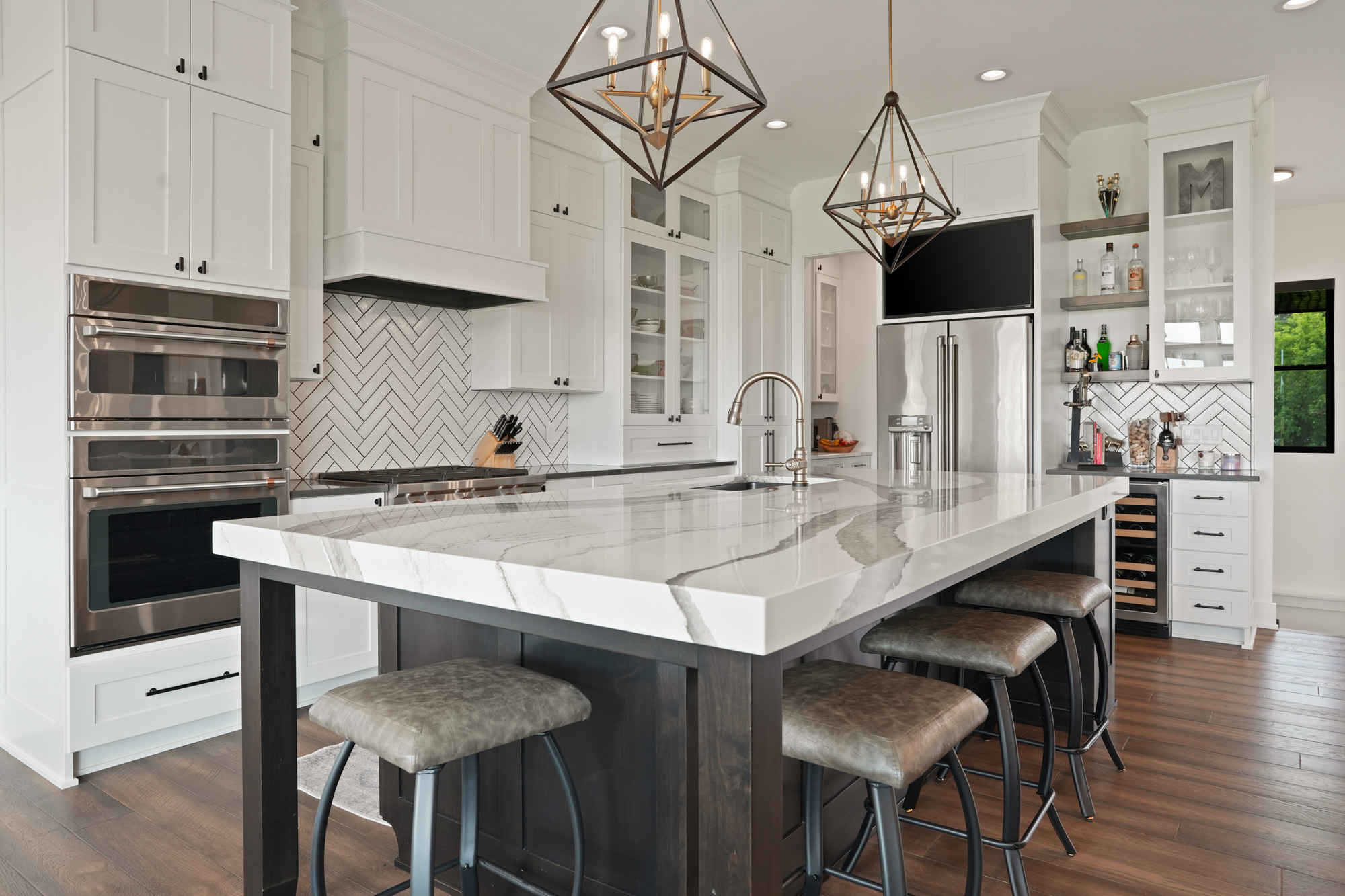 Modern lake house kitchen featuring a large quartz island, stainless steel appliances, and custom cabinetry by lake house builders in Wisconsin.