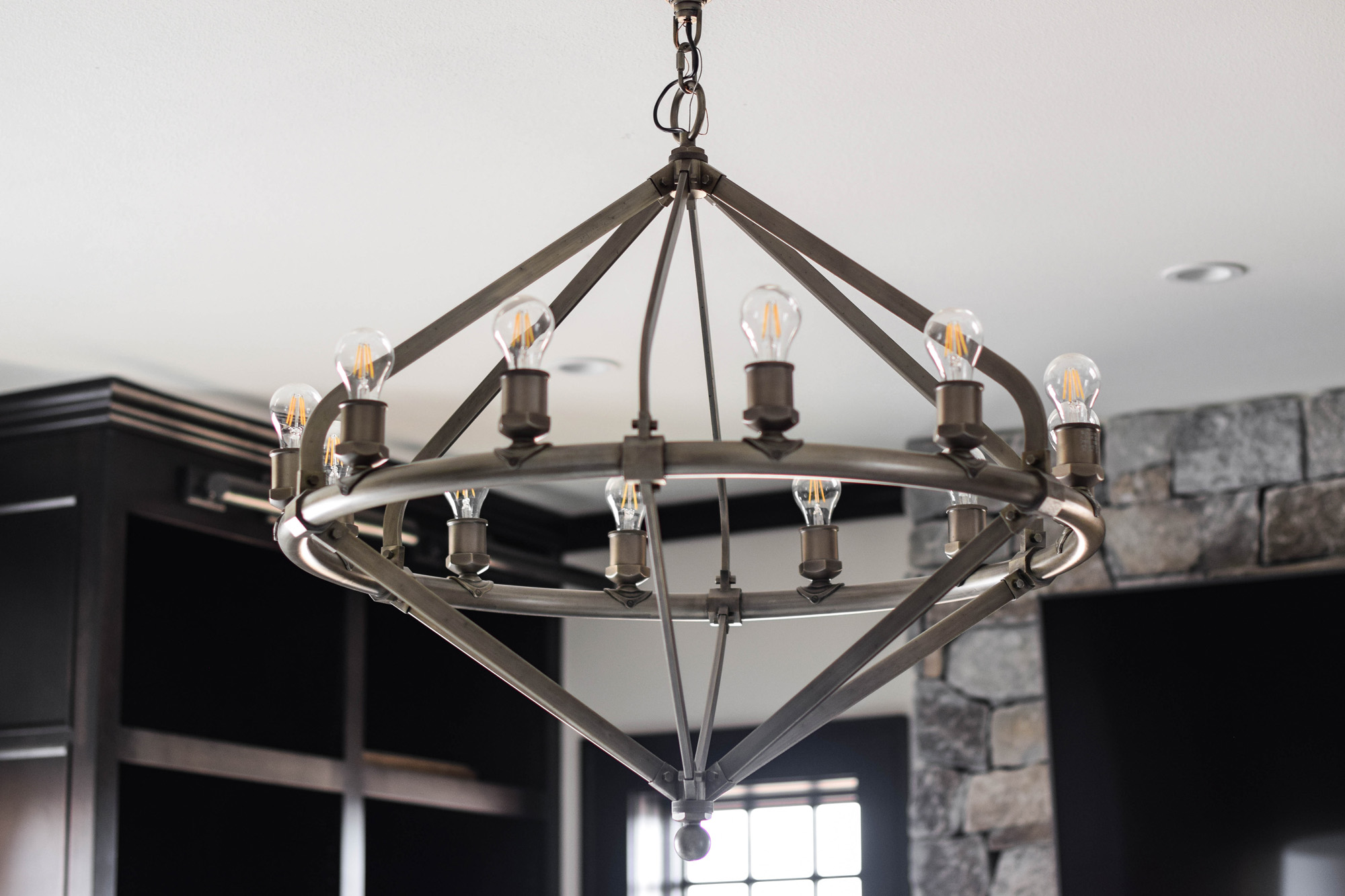 DSC_0404 Close-up of a modern industrial chandelier in a custom-built home by luxury home builders in Brookfield, Wisconsin, featuring exposed bulbs and metal framework.