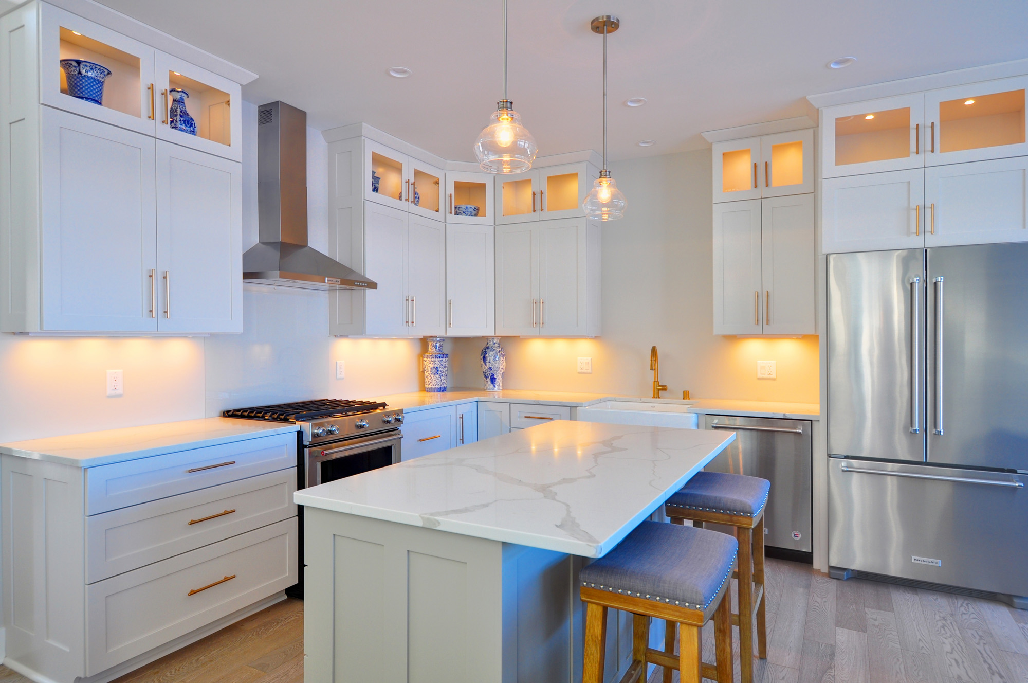 Modern white kitchen with marble countertops, stainless steel appliances, and custom cabinetry designed by luxury home builders in Brookfield, Wisconsin