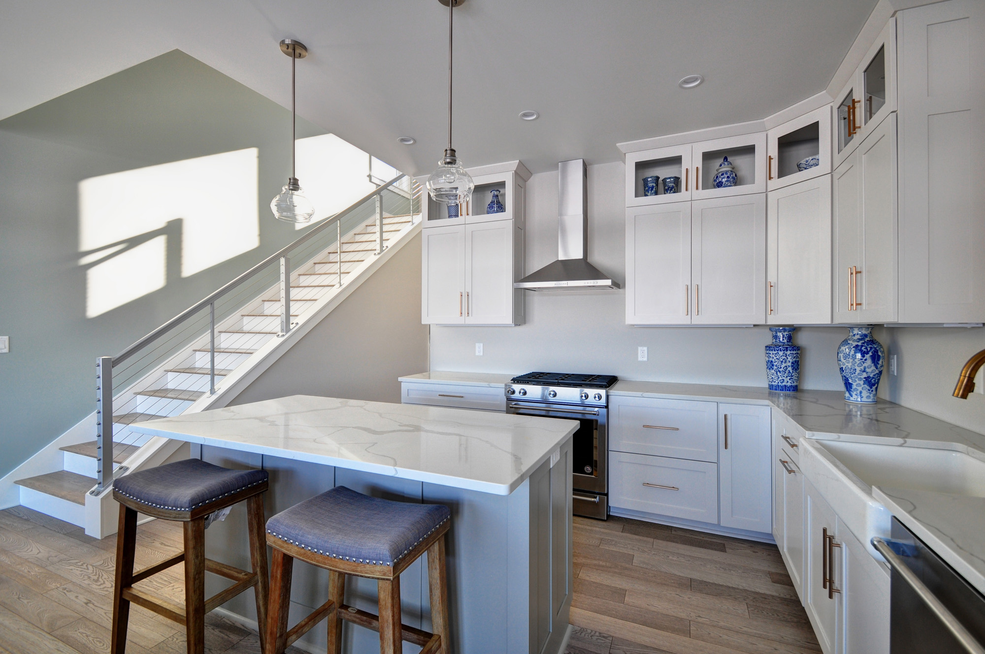 kitchen_ stairs Modern kitchen with quartz island, shaker cabinets, and adjacent staircase, blending function and style in this Wisconsin lake home design.